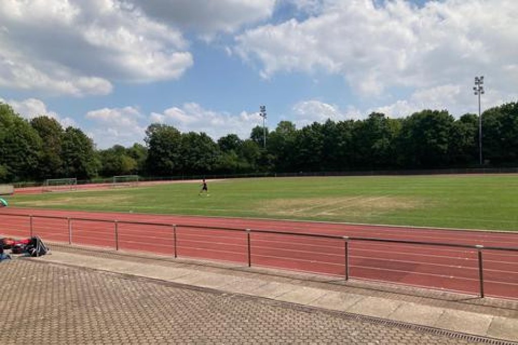sportplatz mit kaputten Rasen und tartanbahn.